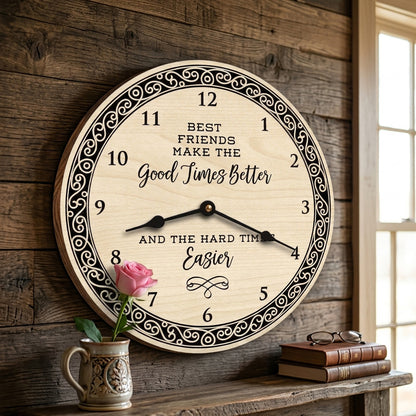 A round wooden wall clock with black decorative numerals and text reading 'Best Friends Make the Good Times Better and the Hard Times Easier,' shown hanging on a rustic wood wall above a shelf with a pink rose in a small vase and stacked books.